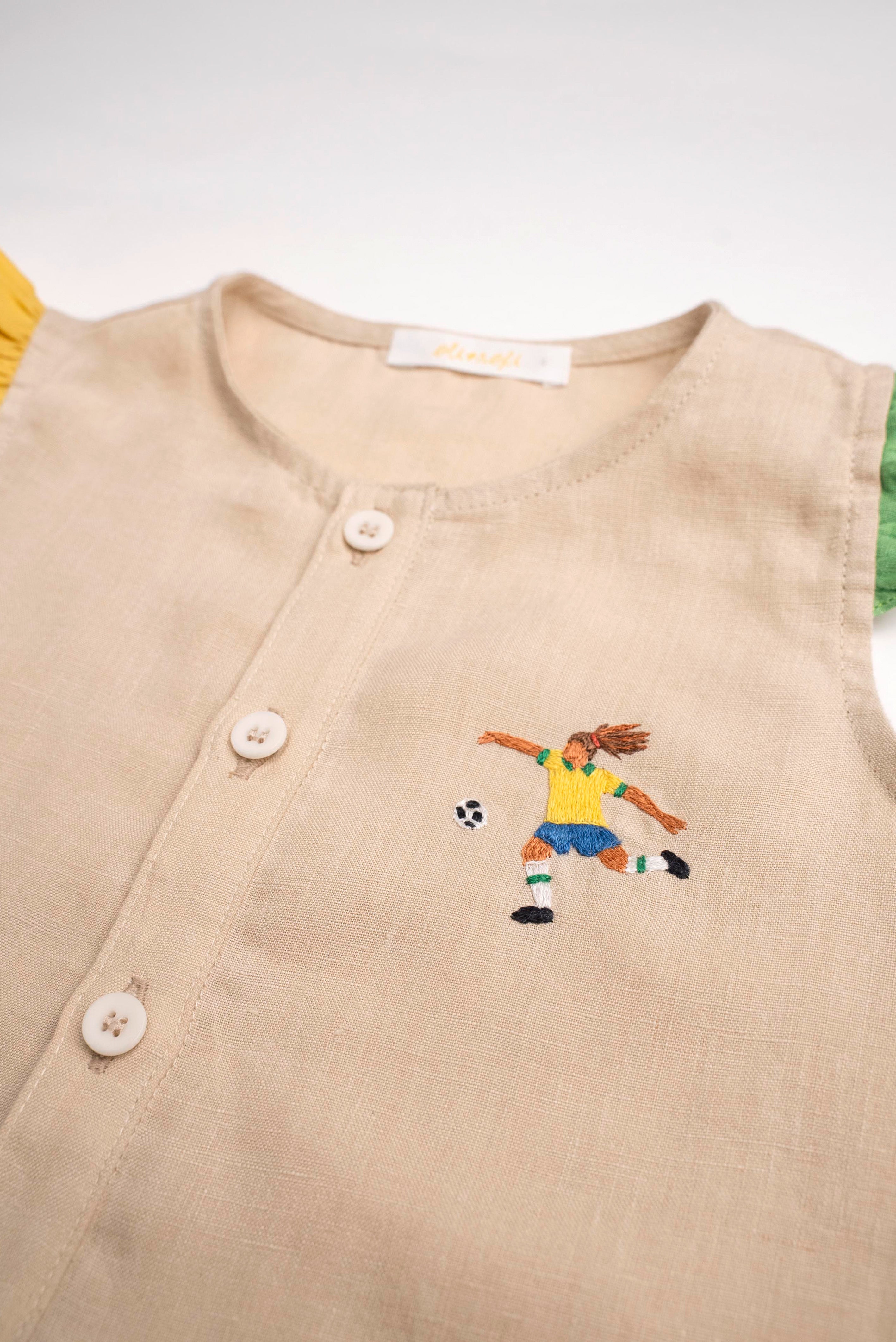Detalhe do bordado à mão de jogadora de futebol em camisa infantil de linho puro