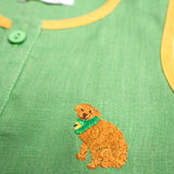 Detalhe do bordado à mão de cachorro caramelo em camisa infantil de linho verde