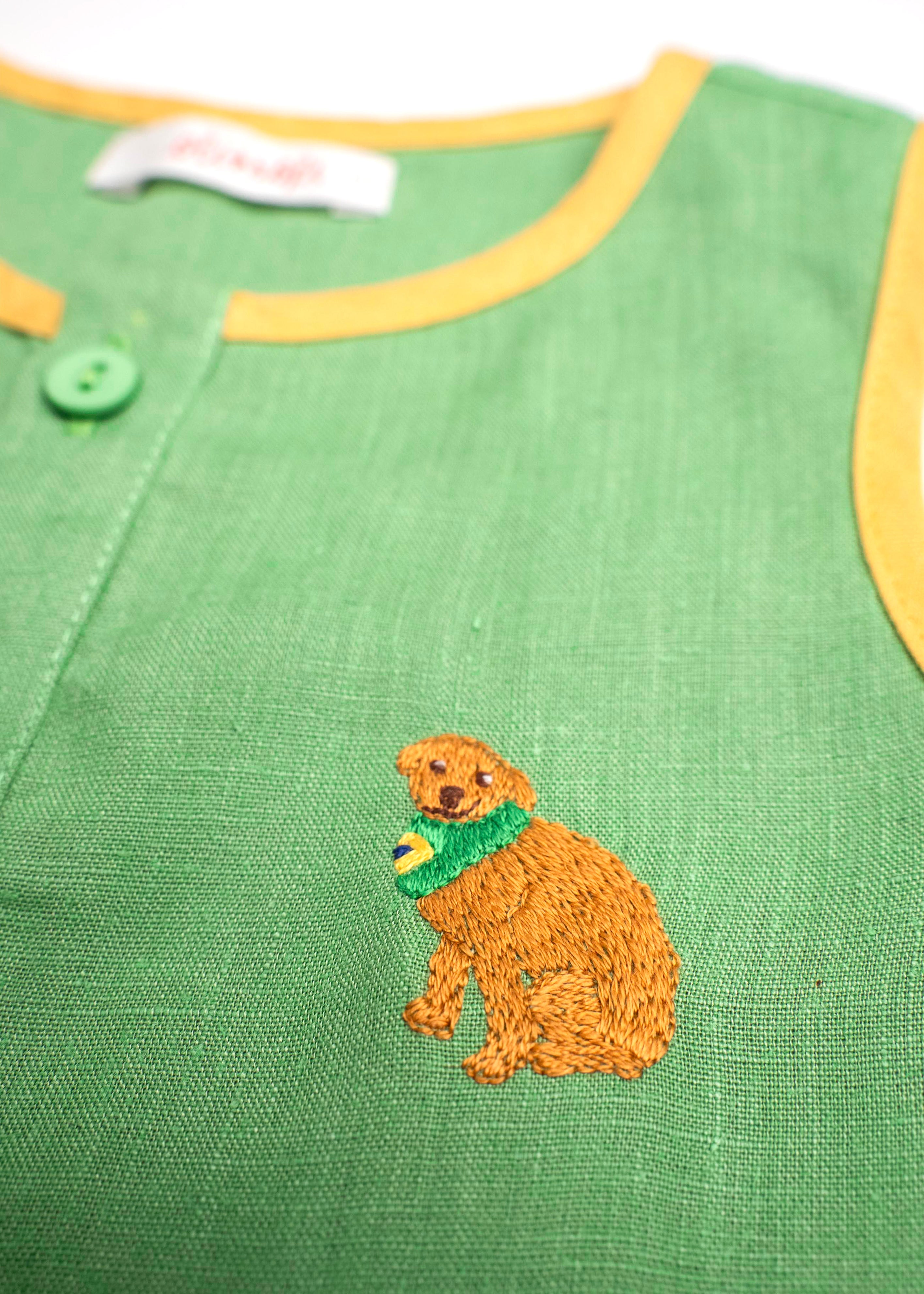 Detalhe do bordado à mão de cachorro caramelo em camisa infantil de linho verde