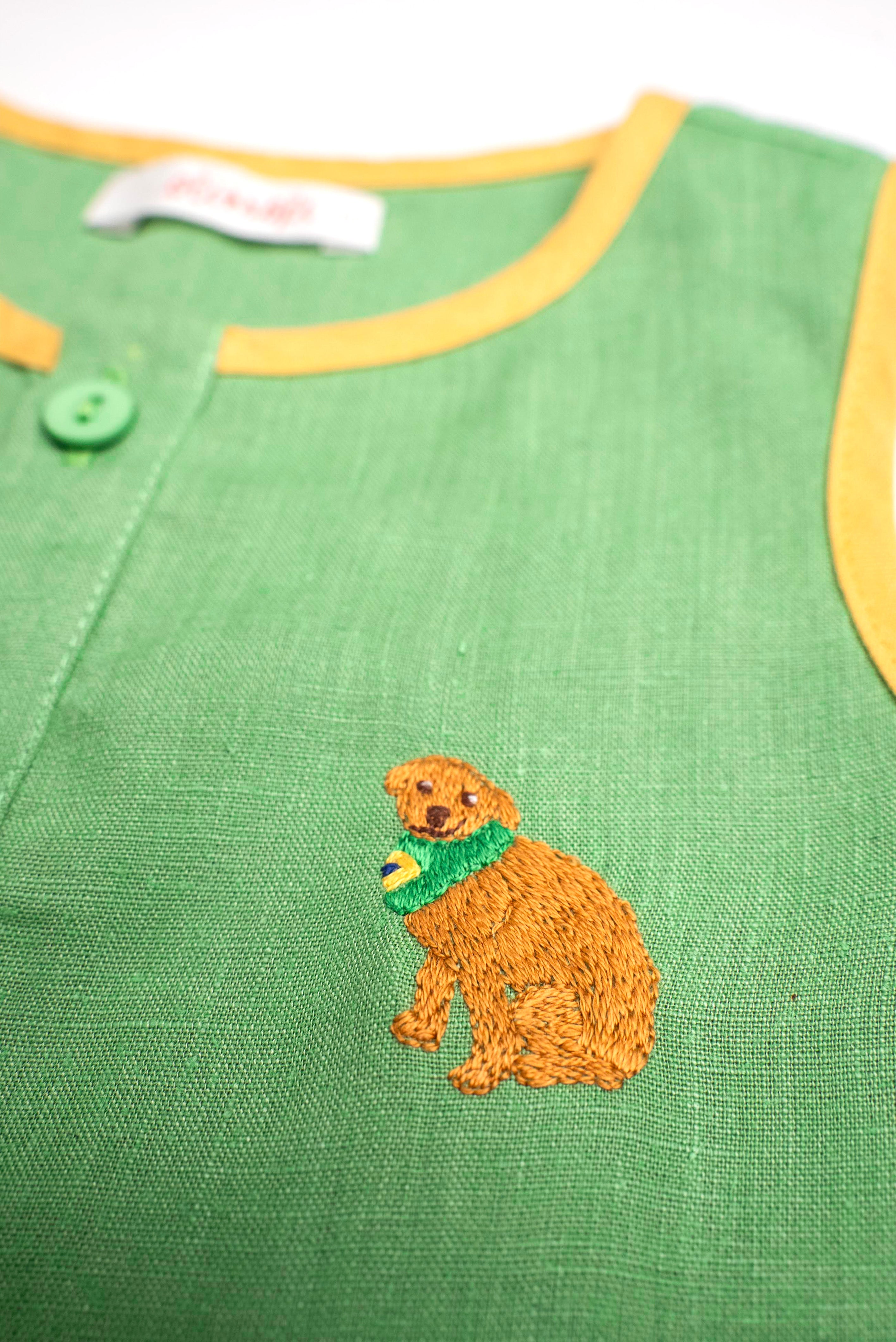 Detalhe do bordado à mão de cachorro caramelo em camisa infantil de linho verde