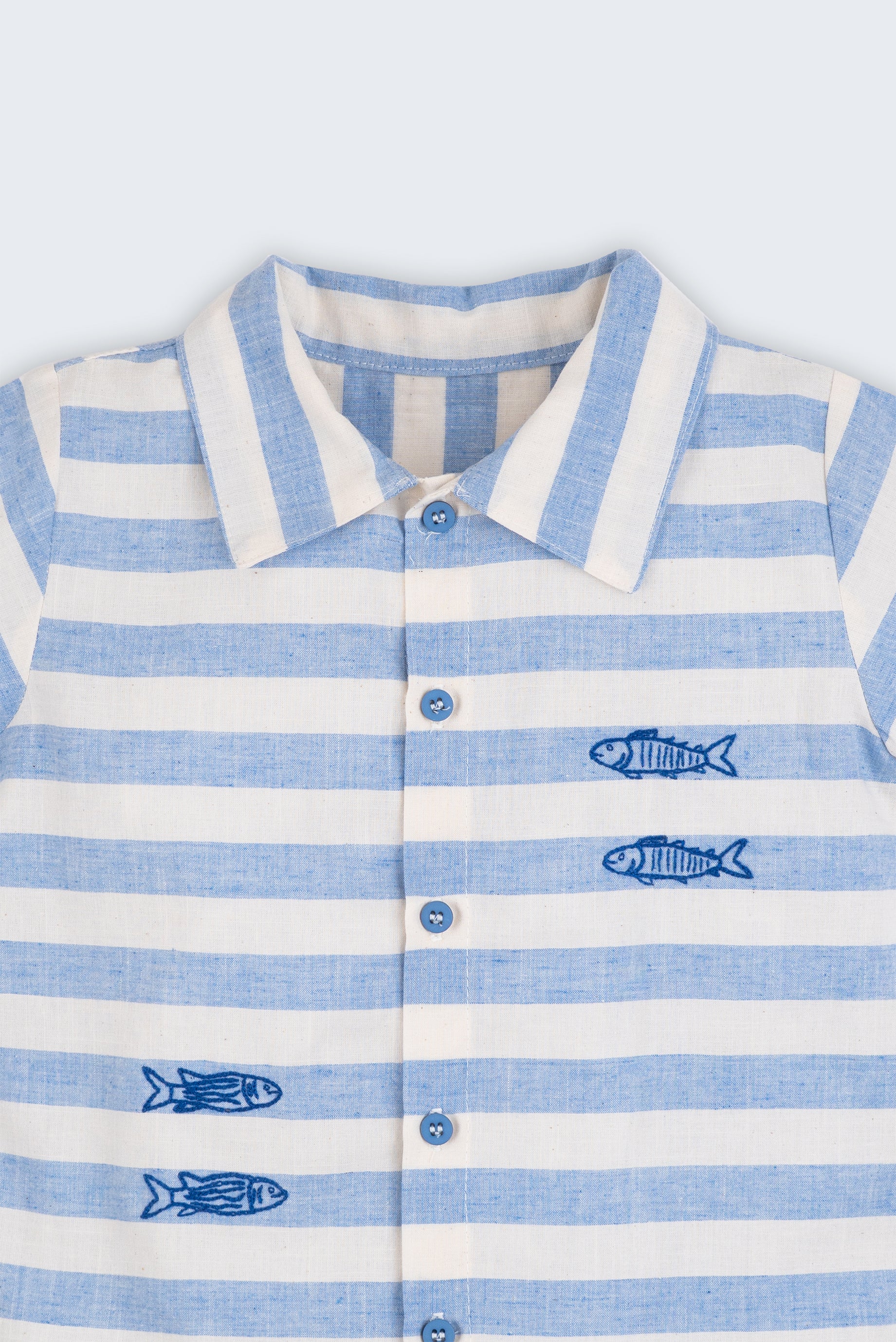 Camisa infantil listrada azul em algodão BCI com peixes bordados, vista de frente em detalhe.