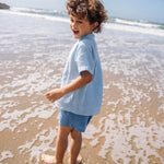 Camisa infantil de linho azul vista de costas no corpo.
