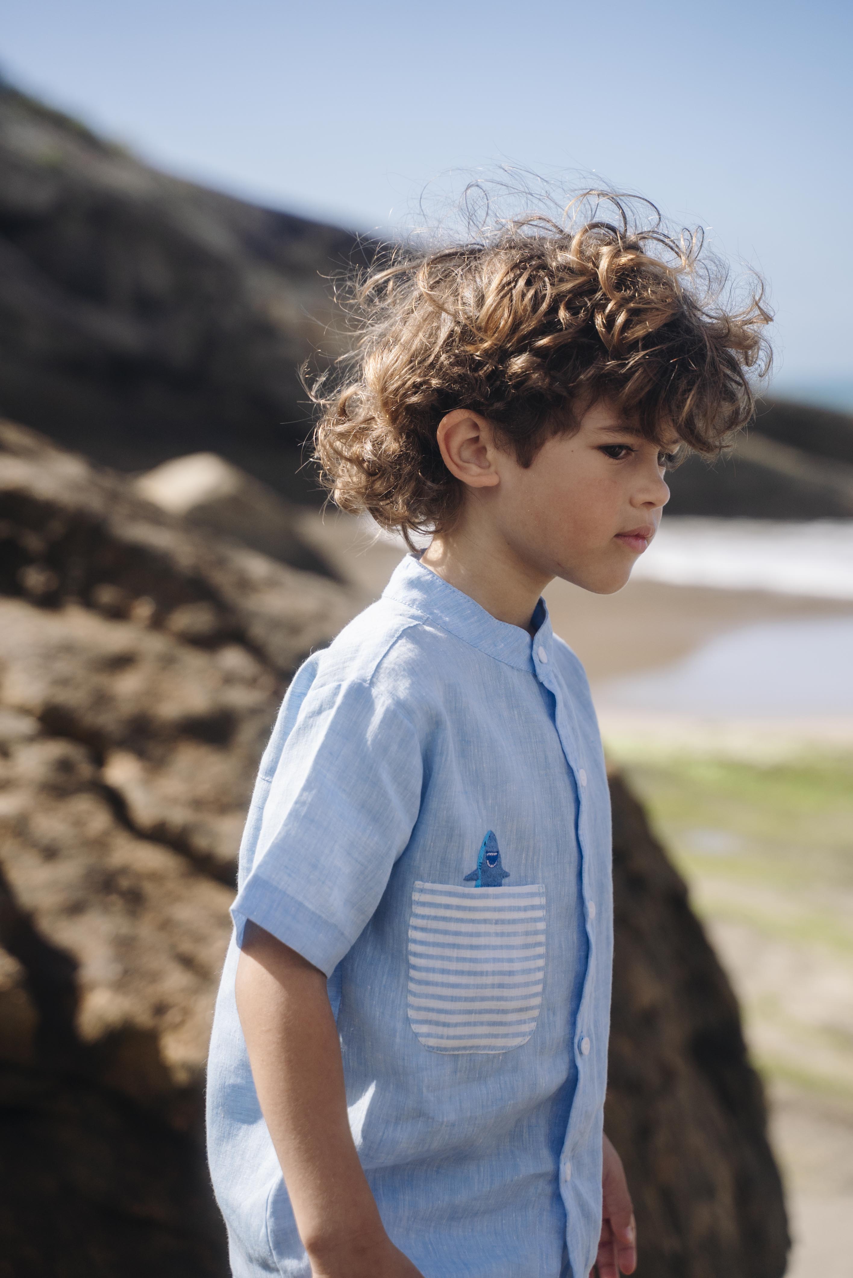 Camisa infantil de linho azul no corpo, bolso listrado e tubarão bordado à mão.