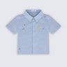 Camisa infantil para menino em puro linho azul claro com bordado à mão de sol, lua, planeta, estrelas e foguete, vista frontal.