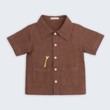 Camisa infantil de menino em linho marrom com bolsos frontais e bordado artesanal de girafa.