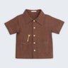 Camisa infantil de menino em linho marrom com bolsos frontais e bordado artesanal de girafa.