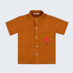 Camisa infantil em linho puro terracota com polvo bordado à mão no bolso, vista de frente; para meninos e meninas.