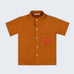 Camisa infantil em linho puro terracota com polvo bordado à mão no bolso, vista de frente; para meninos e meninas.