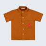 Camisa infantil em linho puro terracota com polvo bordado à mão no bolso, vista de frente; para meninos e meninas.