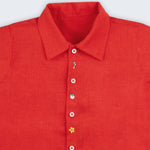 Camisa infantil em linho vermelho com bordado natalino à mão e botões brancos, vista em detalhe.