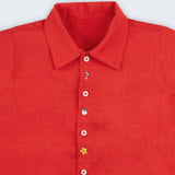Camisa infantil em linho vermelho com bordado natalino à mão e botões brancos, vista em detalhe.