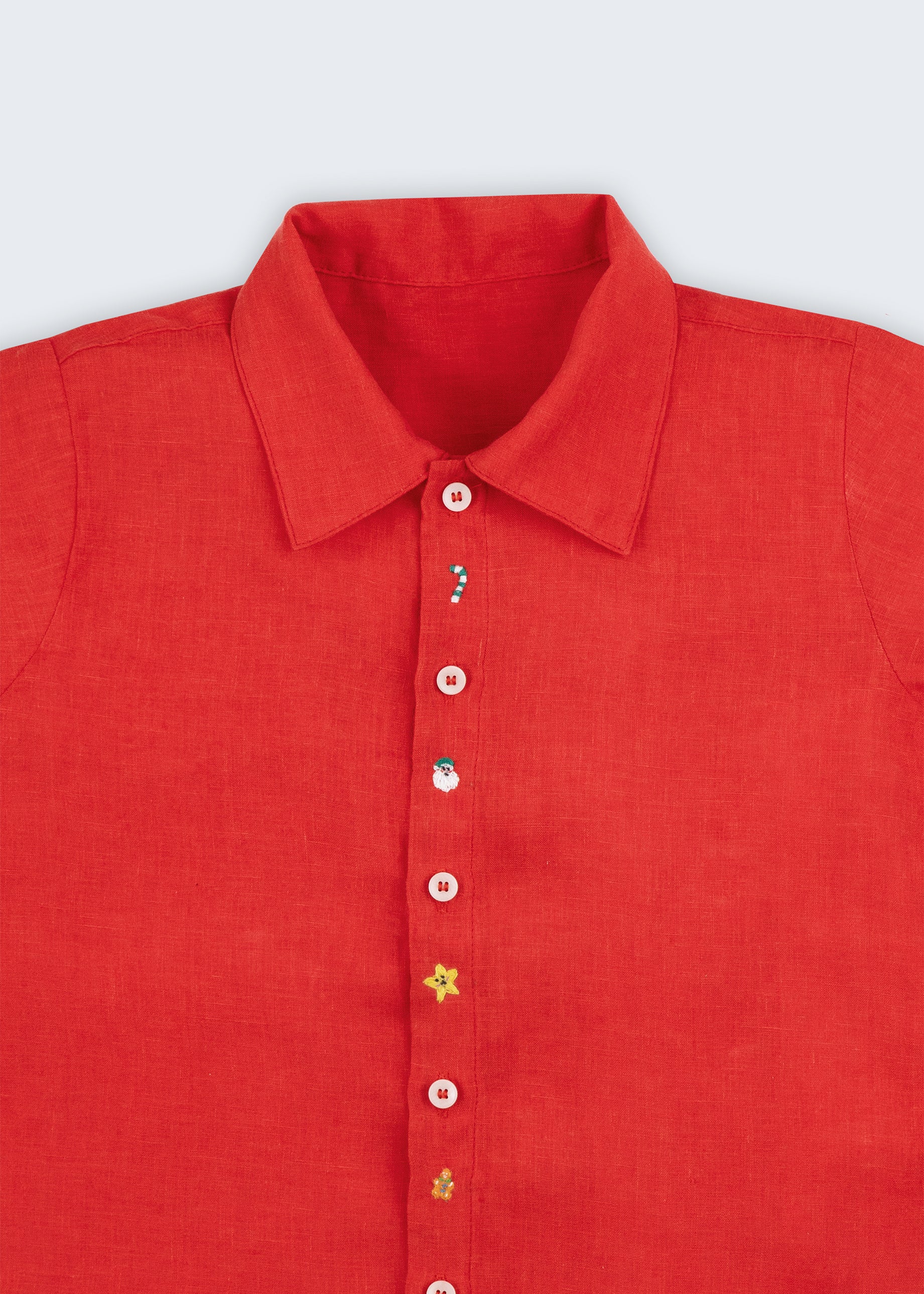 Camisa infantil em linho vermelho com bordado natalino à mão e botões brancos, vista em detalhe.
