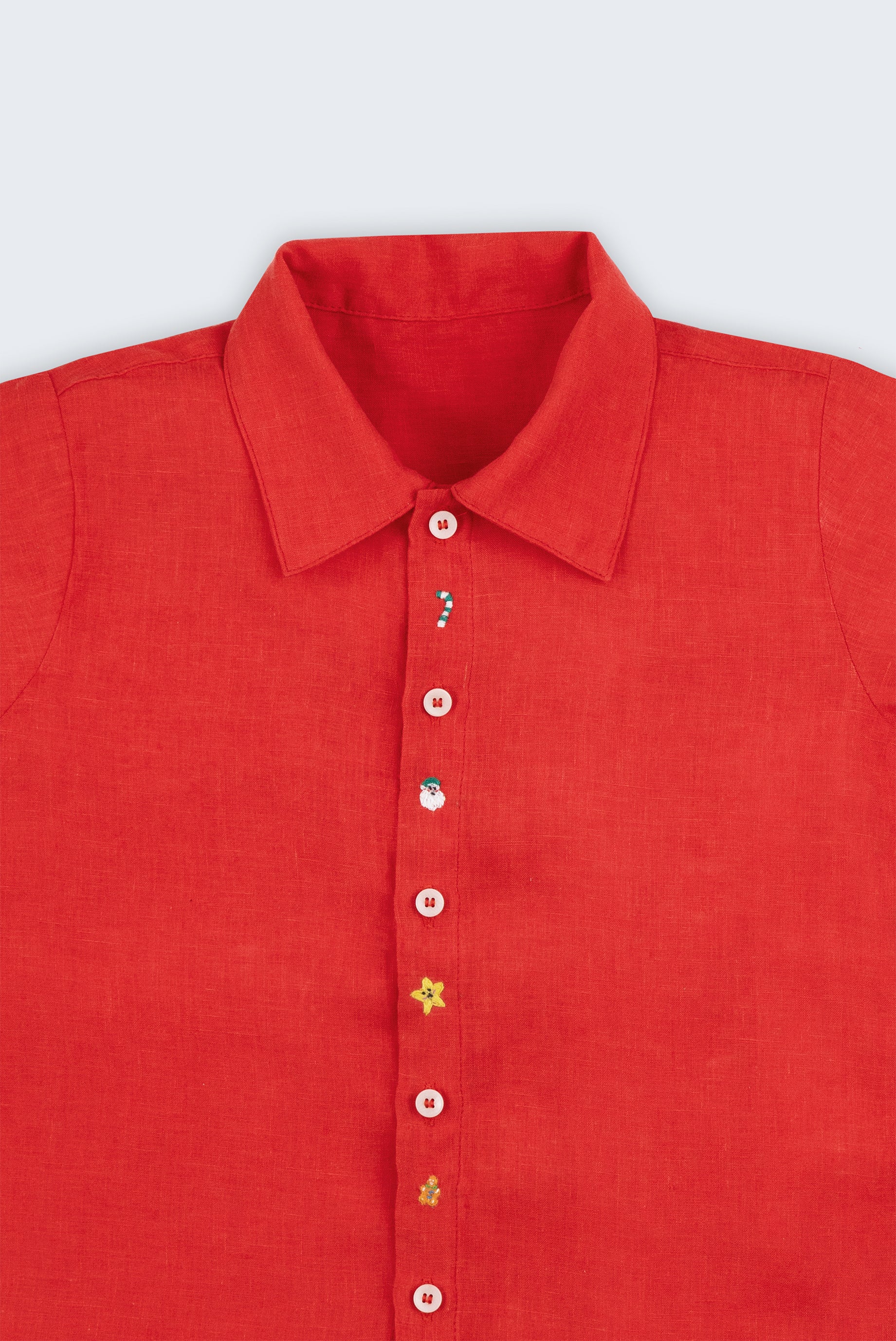 Camisa infantil em linho vermelho com bordado natalino à mão e botões brancos, vista em detalhe.