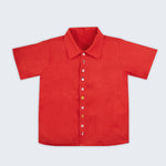 Vista frontal da camisa infantil menino em linho vermelho com pequenos bordados à mão natalinos.