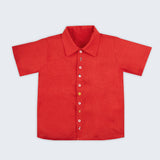 Vista frontal da camisa infantil menino em linho vermelho com pequenos bordados à mão natalinos.