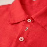 Close da bengala natalina e Papai Noel bordados à mão em camisa infantil vermelha de linho.