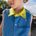 Menino usando camisa infantil em linho azul com gola amarelo lima e bordados de barquinhos coloridos espalhados pela pala, ombro e bolso feitos à mão.