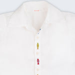 Camisa infantil em linho branco com bordados feitos à mão de peixes coloridos entre os botões, vista de frente em detalhe.