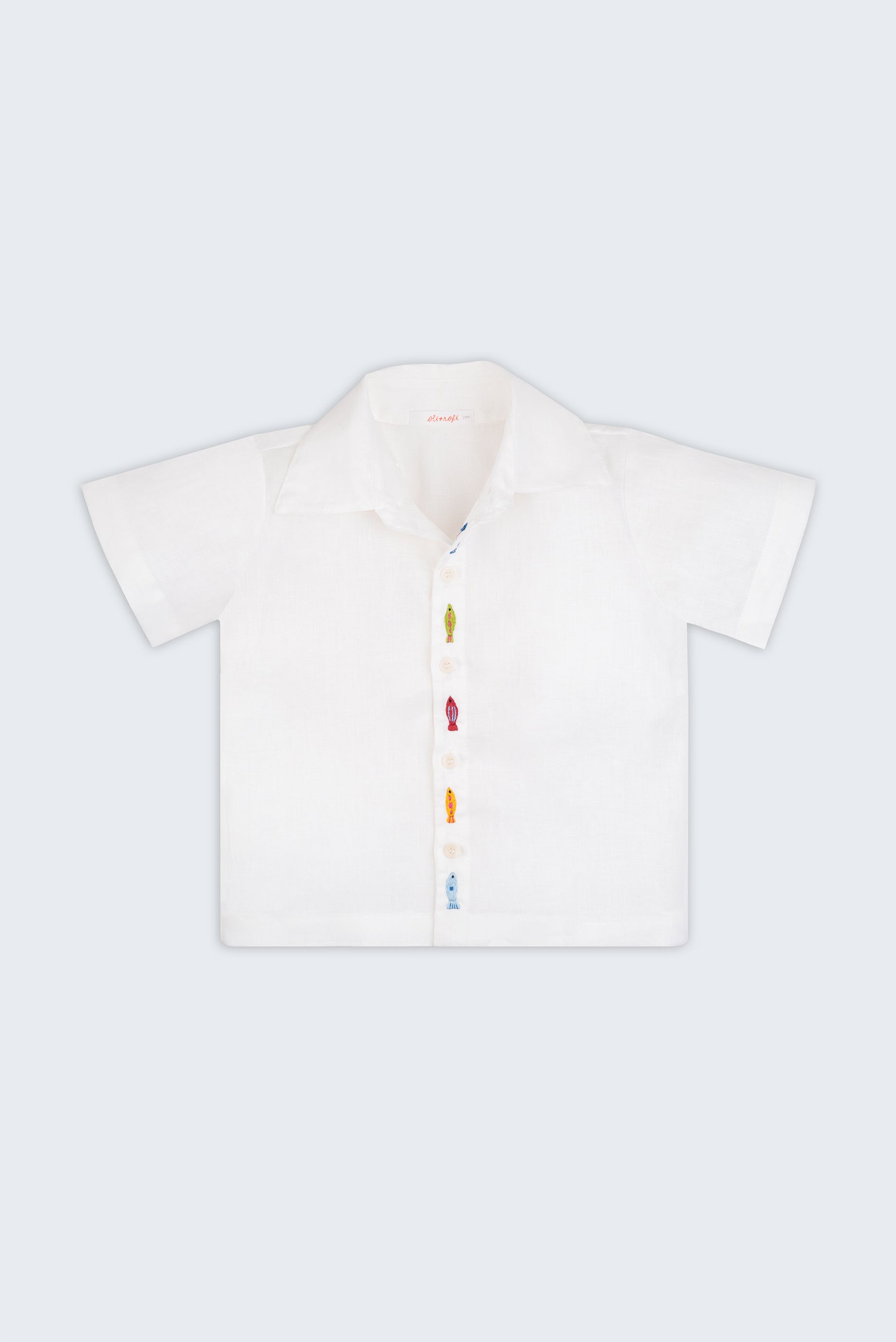 Camisa infantil em linho branco com bordados de peixes coloridos alinhados verticalmente entre os botões, vista de frente.