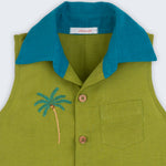 Camisa infantil em linho verde com gola azul petróleo e bordado no peito de coqueiro tropical feito à mão, vista de frente em detalhe.