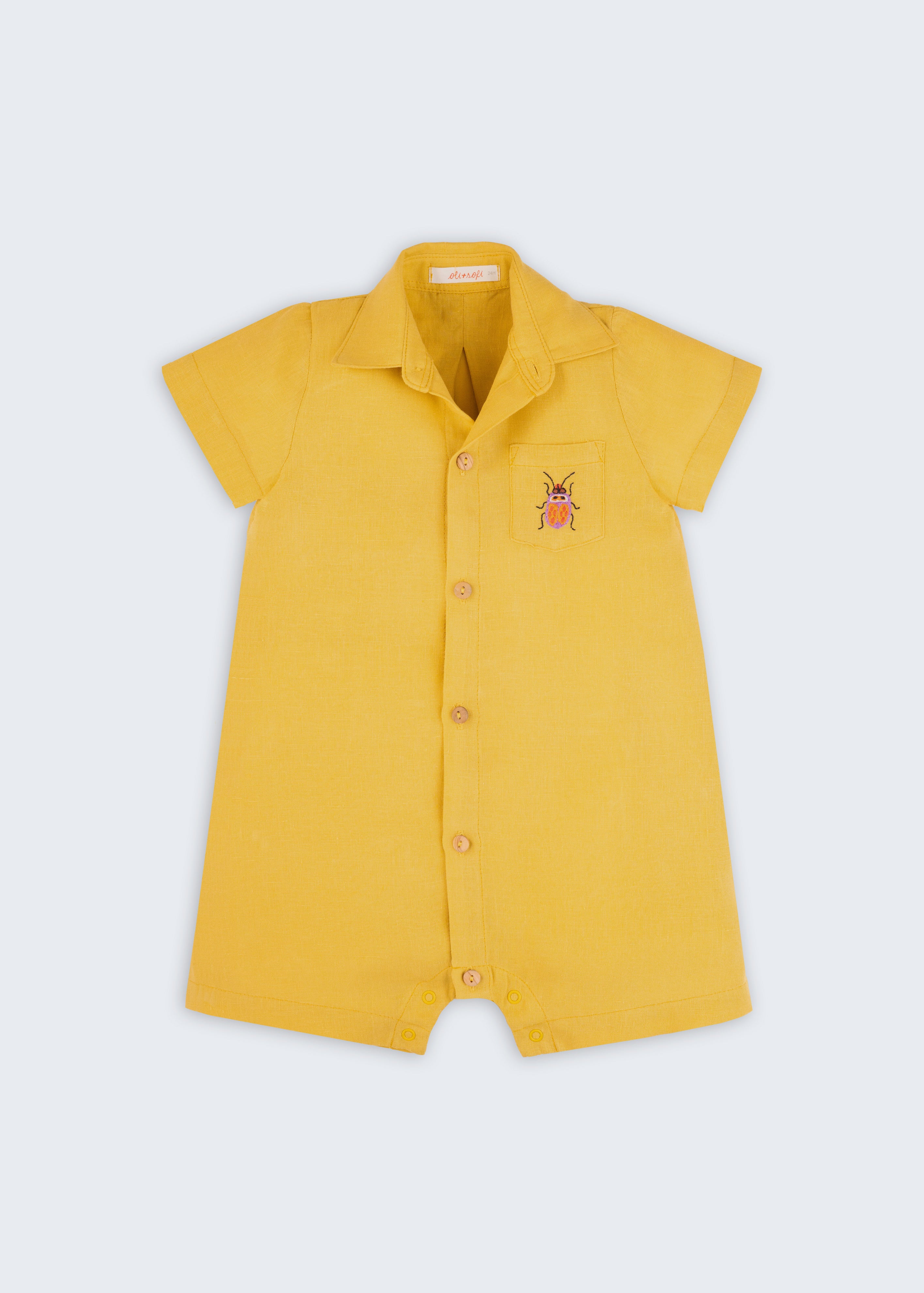Macacão infantil unissex em linho amarelo com bordado de besouro, visto de frente.