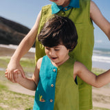 Menino usando macaquinho infantil em linho bicolor azul e verde com tartaruga bordada à mão, combinando com irmão.