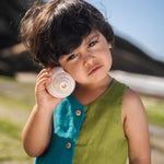 Menino usando macaquinho infantil em linho bicolor azul e verde com tartaruga bordada à mão, em close.