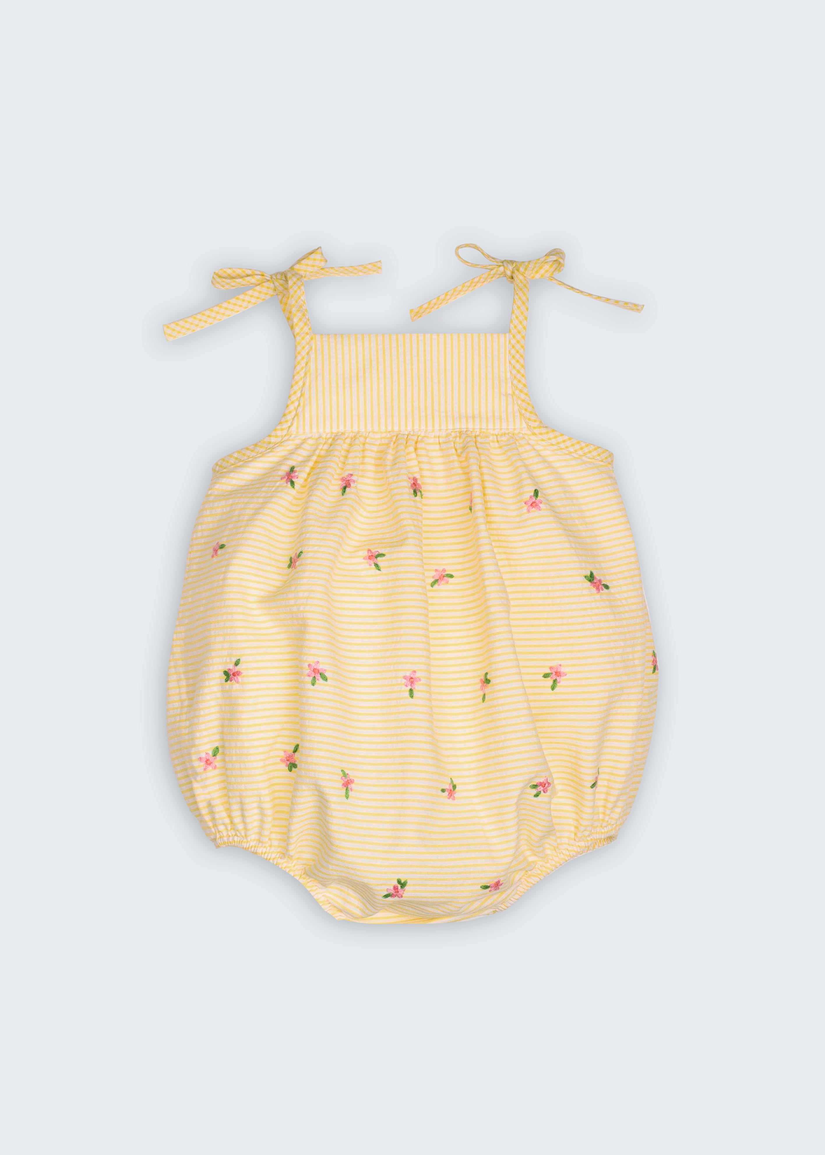 Macaquinho Flora para bebê em algodão anarruga amarelo e branco, com alças de amarrar e flores bordadas à mão.