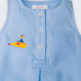 Detalhe do macaquinho de bebê azul em linho com botões brancos frontais, bolso no peito e bordado de Yellow Submarine, dos Beatles.
