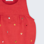 Detalhe dos bordados manuais natalinos em macaquinho de bebê vermelho de linho.