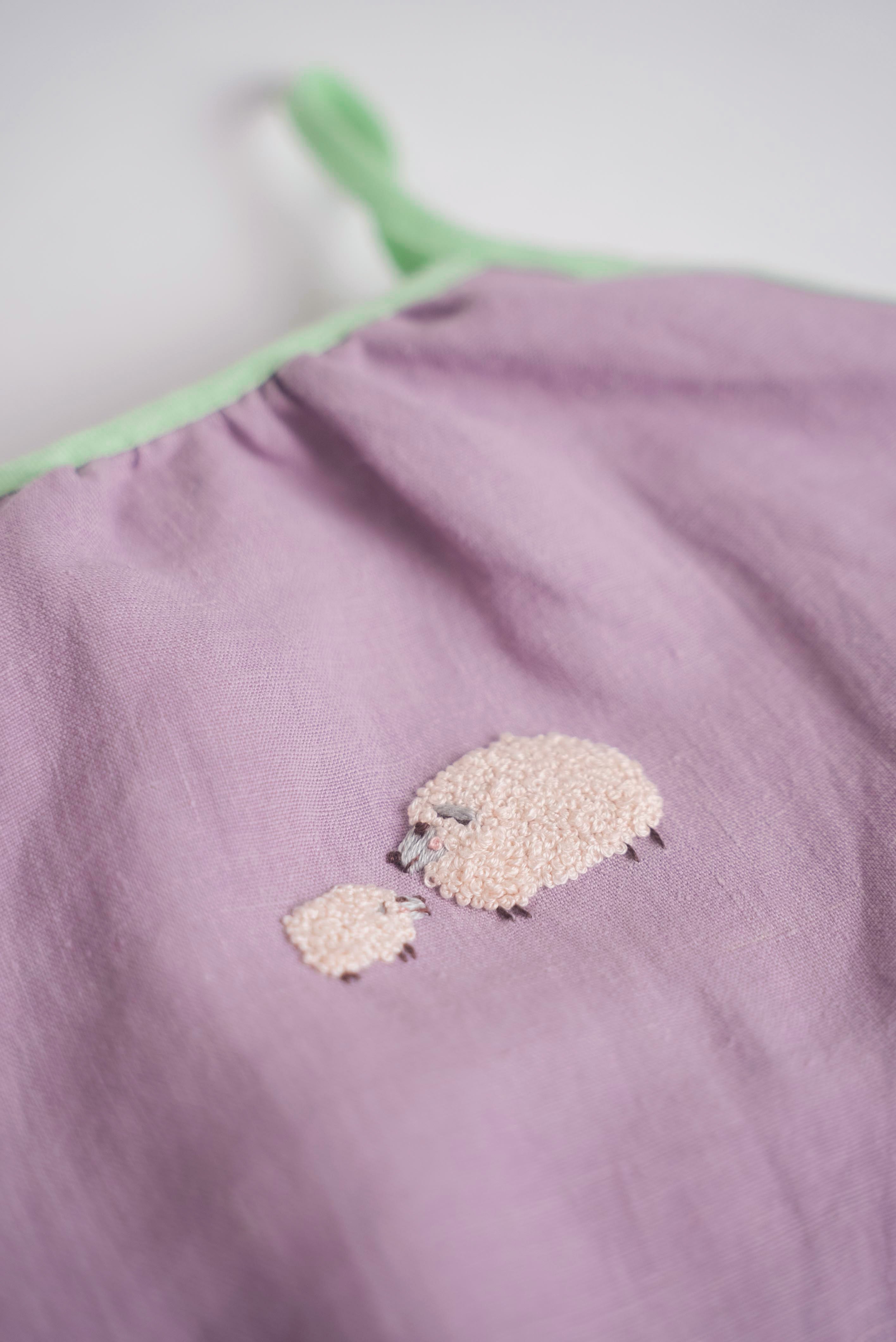 Bordado artesanal de ovelha e filhote em macaquinho infantil de linho lilás.