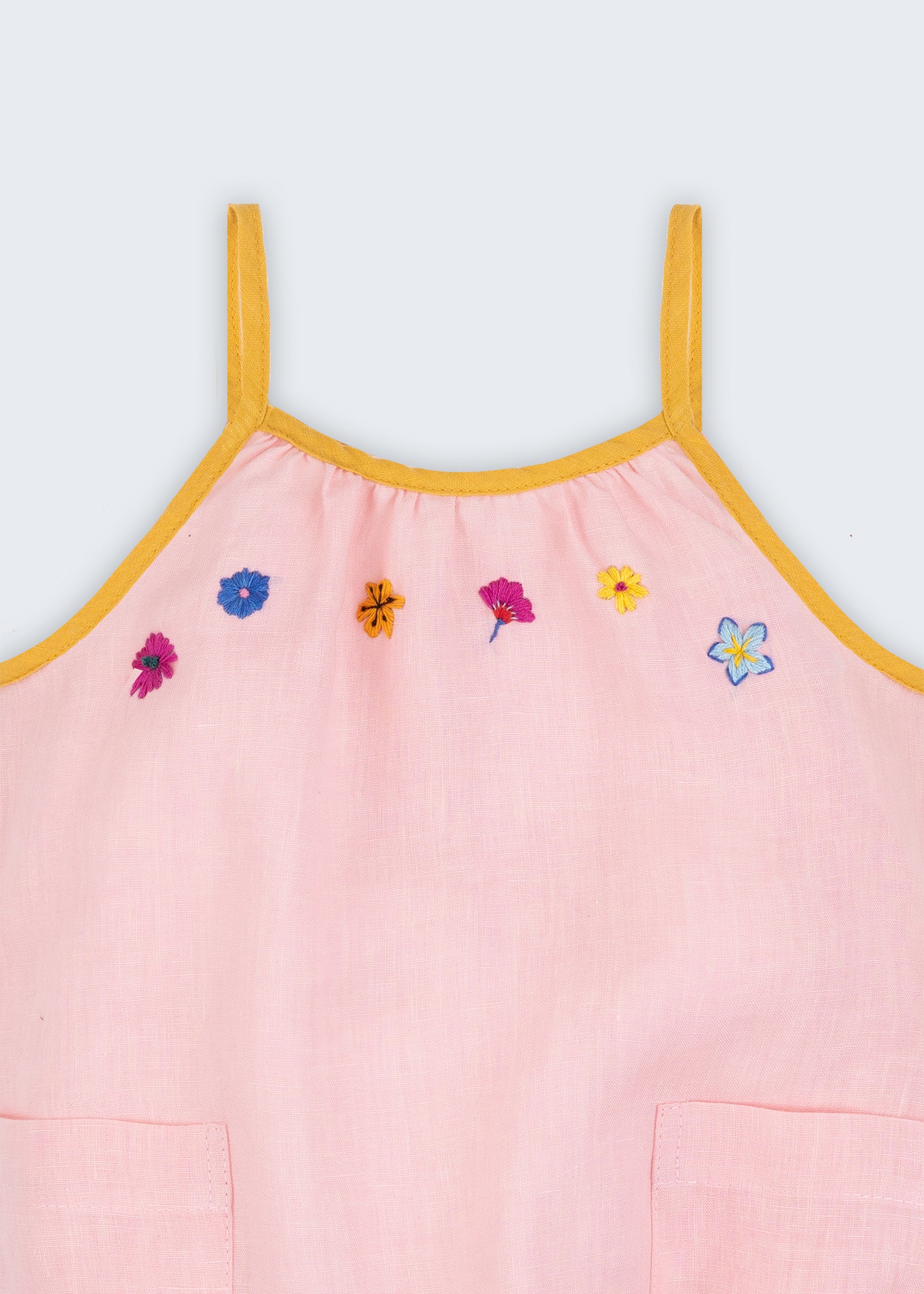 Macaquinho de bebê menina em linho rosa com flores bordadas à mão e alças finas com viés amarelo em detalhe.