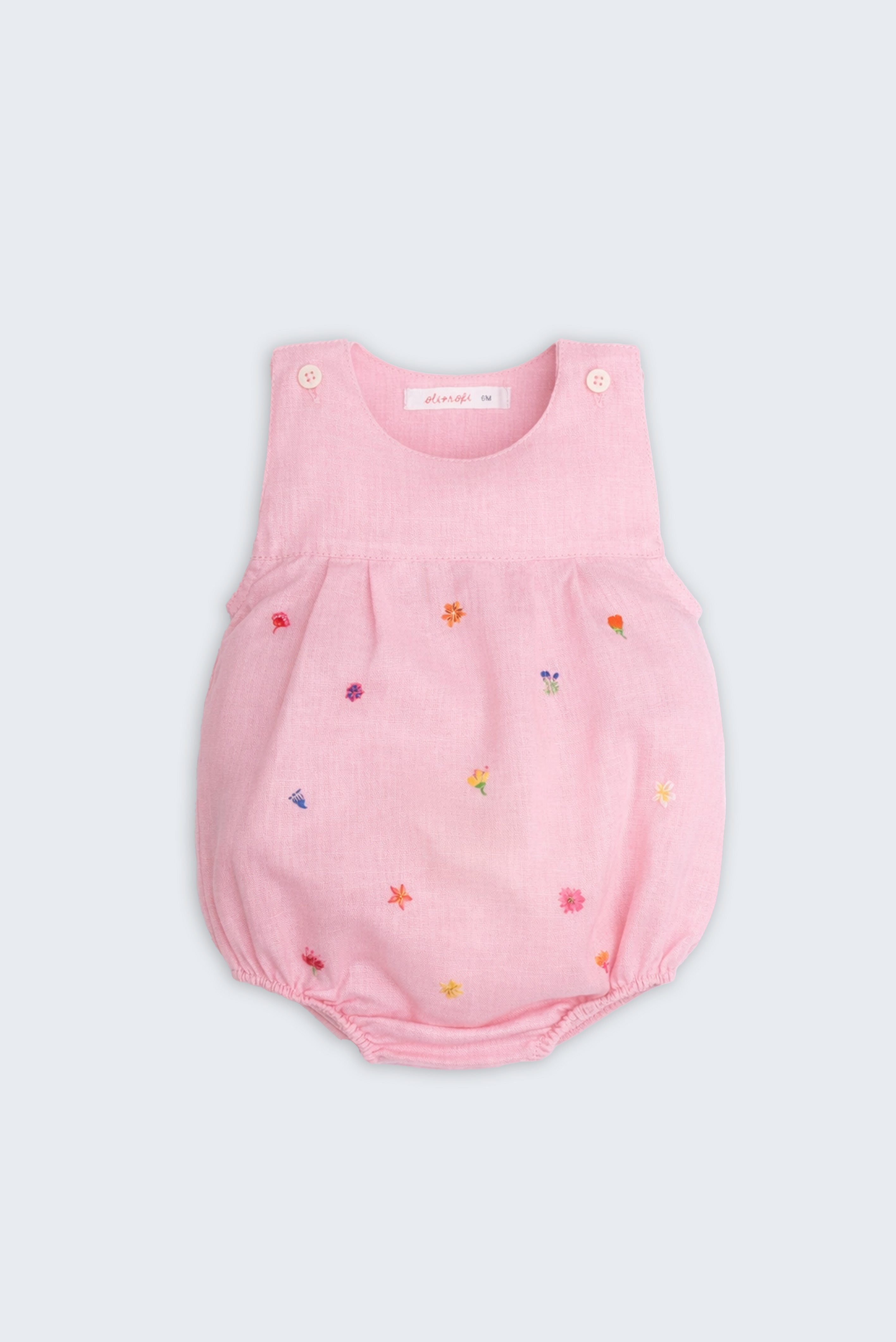 Macaquinho infantil de menina em linho rosa com bordado artesanal de pequenas flores coloridas.