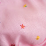 Flor bordada à mão em macaquinho infantil de linho rosa para bebê.