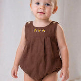 Bebê menino usando macaquinho infantil em linho marrom com bordado à mão de abelhas, também conhecido como romper.