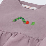 Detalhe do bordado à mão de lagarta verde comendo folha em macaquinho bebê estilo romper de puro linho lilás.