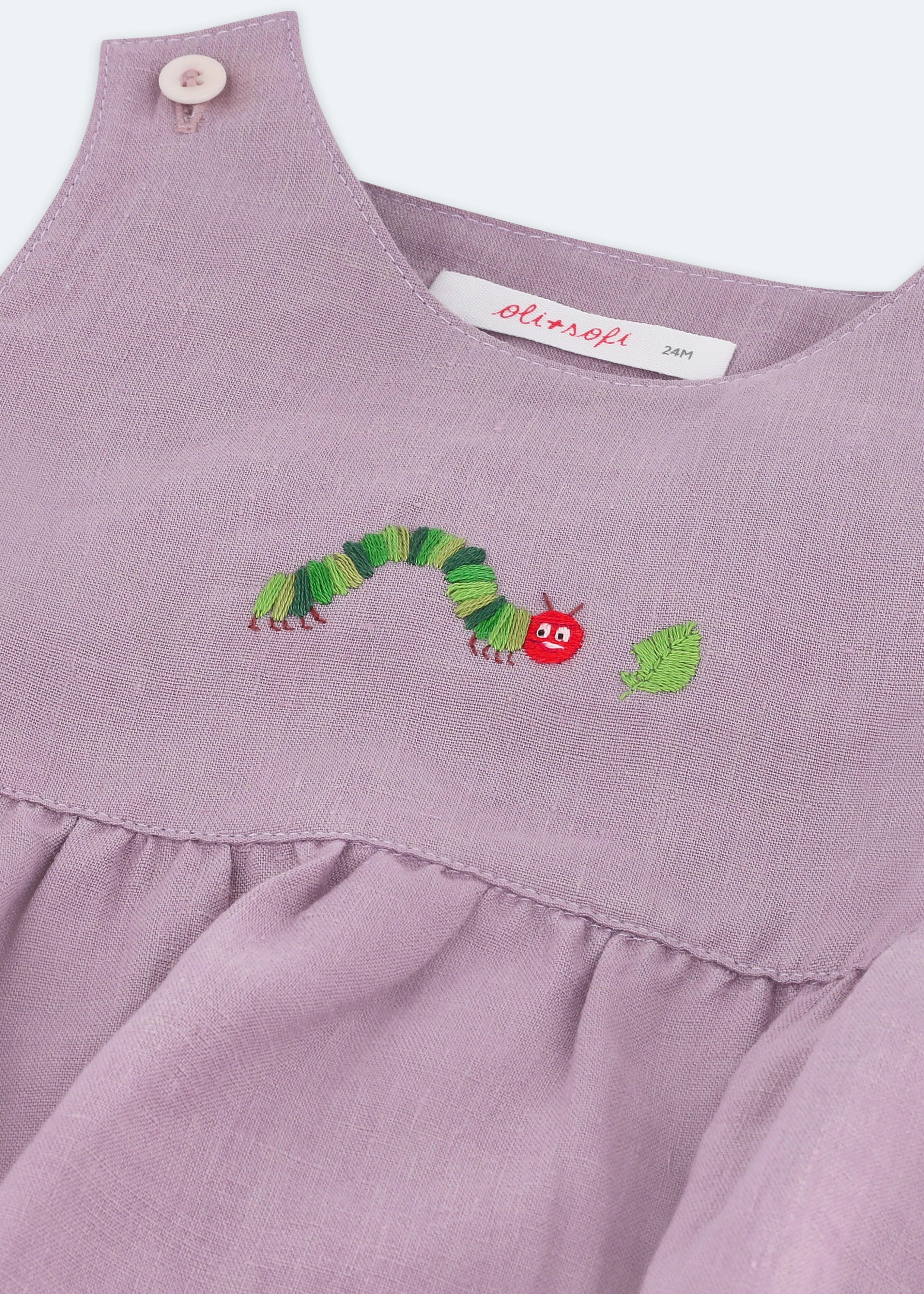 Detalhe do bordado à mão de lagarta comilona em macaquinho bebê estilo romper de puro linho lilás.