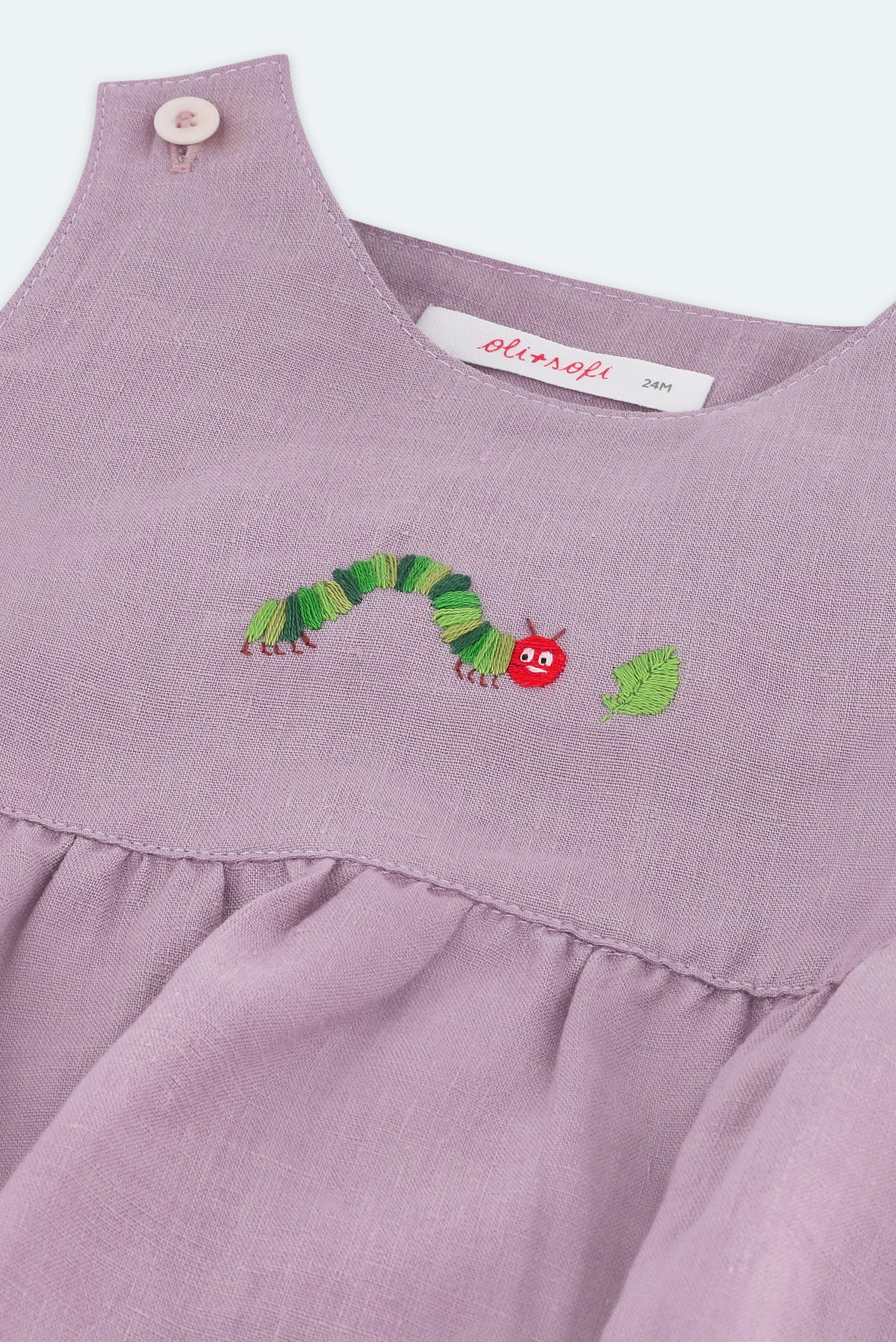 Detalhe do bordado à mão de lagarta comilona em macaquinho bebê estilo romper de puro linho lilás.