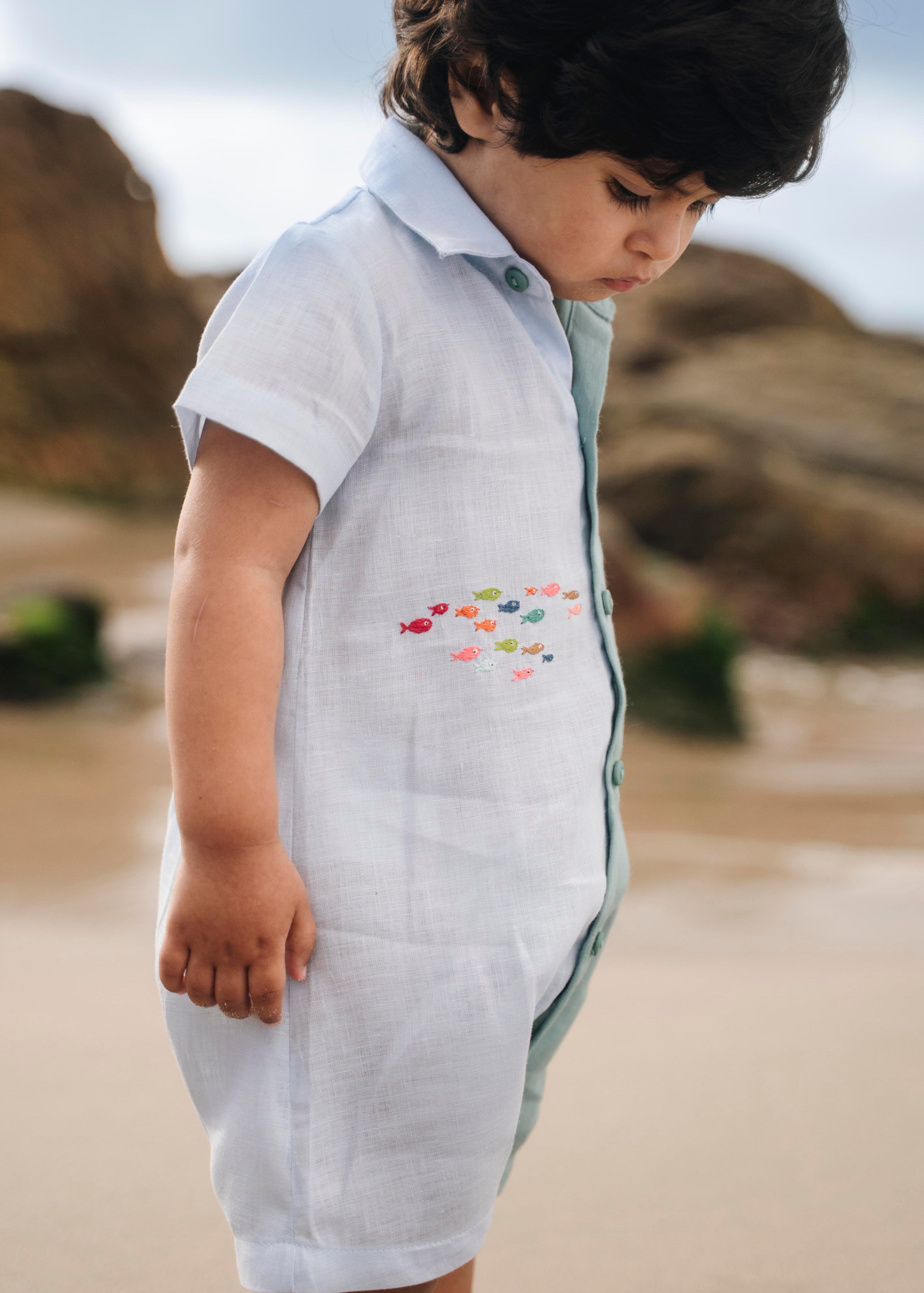 Menino com macaquinho de linho bicolor com cardume de peixes coloridos bordado.