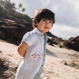 Menino com macaquinho de linho bicolor azul e verde com cardume de peixes bordado.