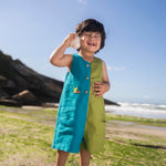 Menino usando macaquinho infantil em linho bicolor azul e verde com tartaruga bordada à mão.