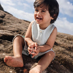 Menino sentado com macaquinho infantil em linho gelo.