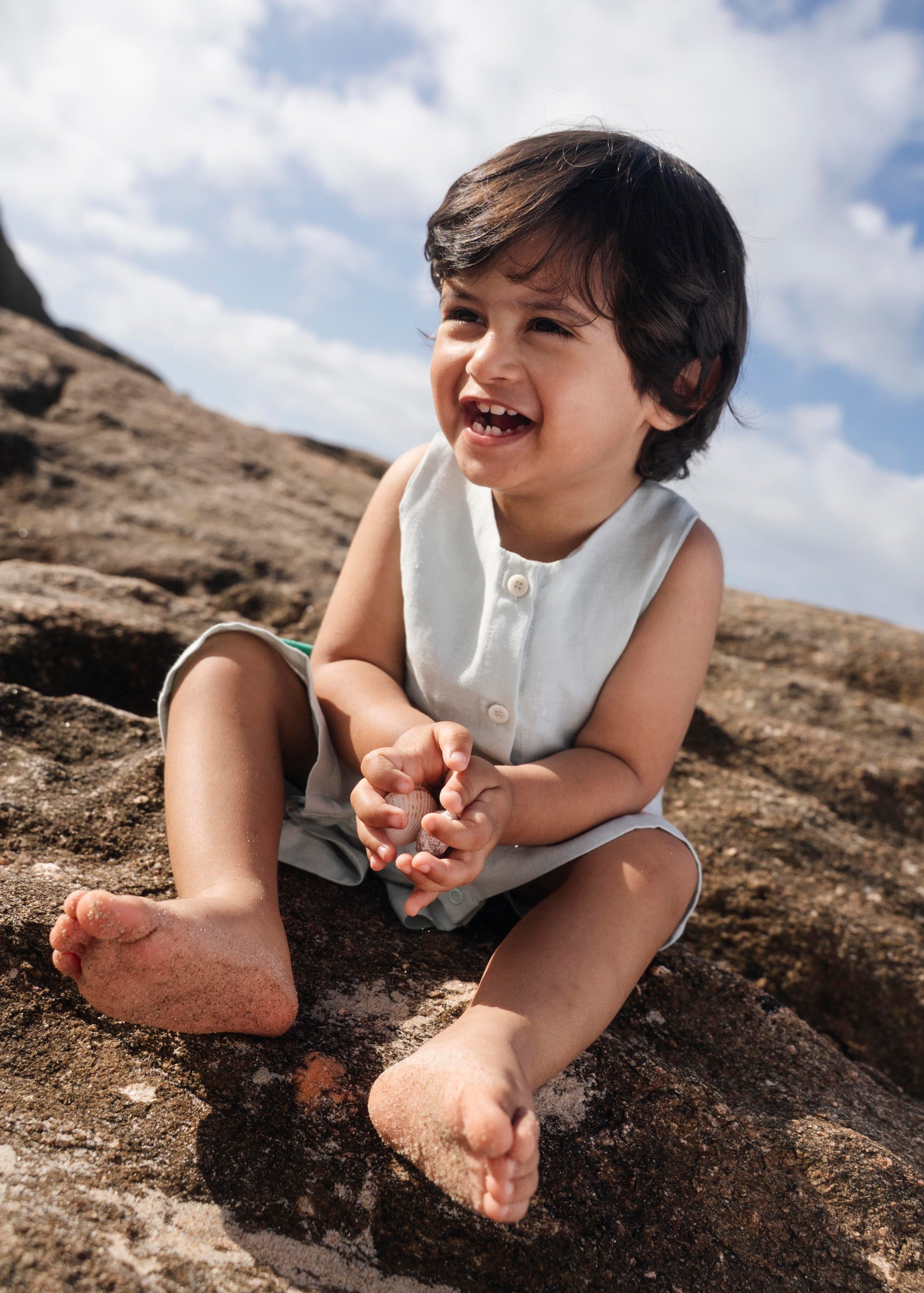 Menino sentado com macaquinho infantil em linho gelo.