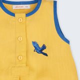 Macaquinho bebê em linho amarelo com acabamento azul e arara azul bordada à mão no peito, visto em detalhe