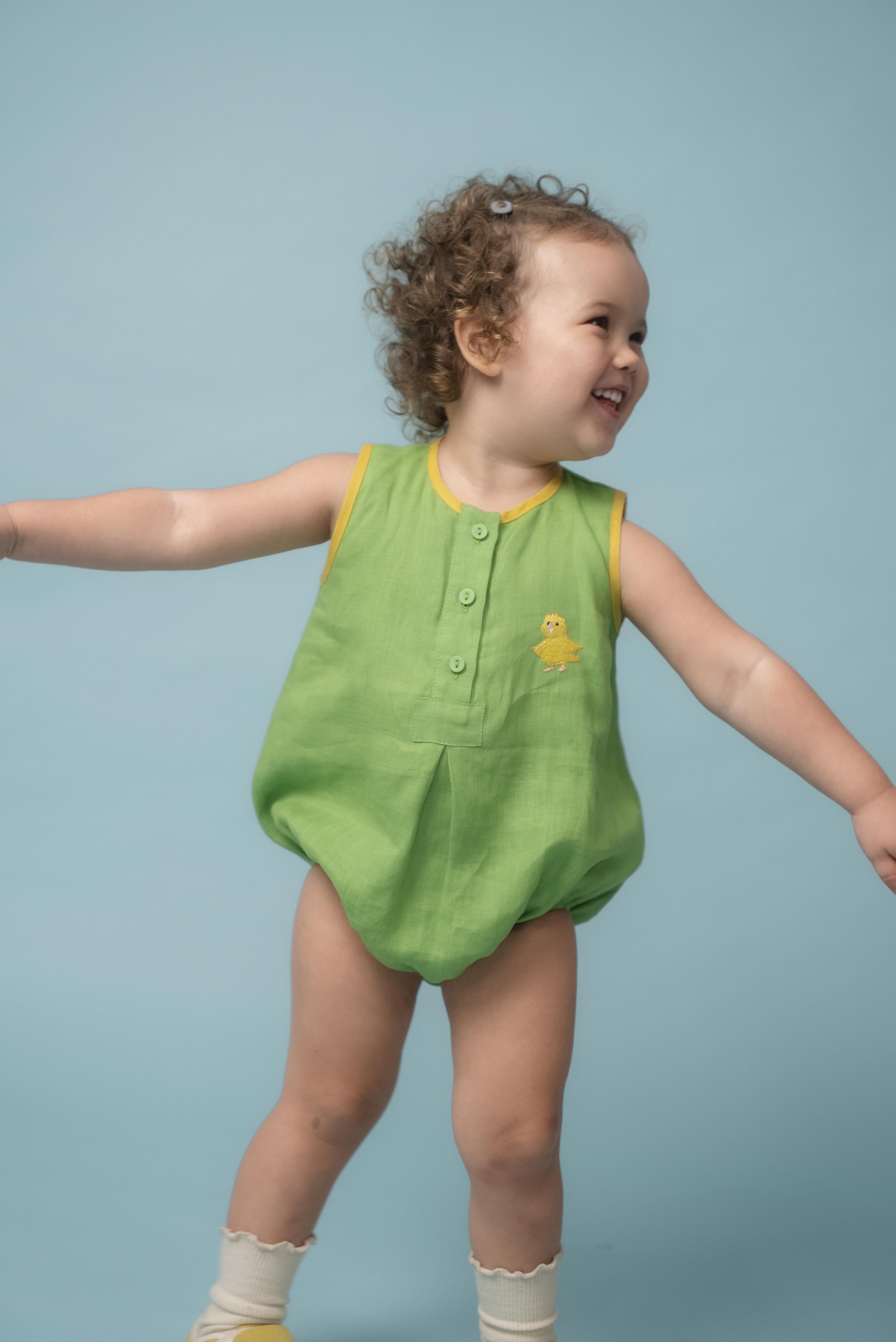 Bebê usando macaquinho infantil verde e amarelo em linho puro com canarinho bordado à mão