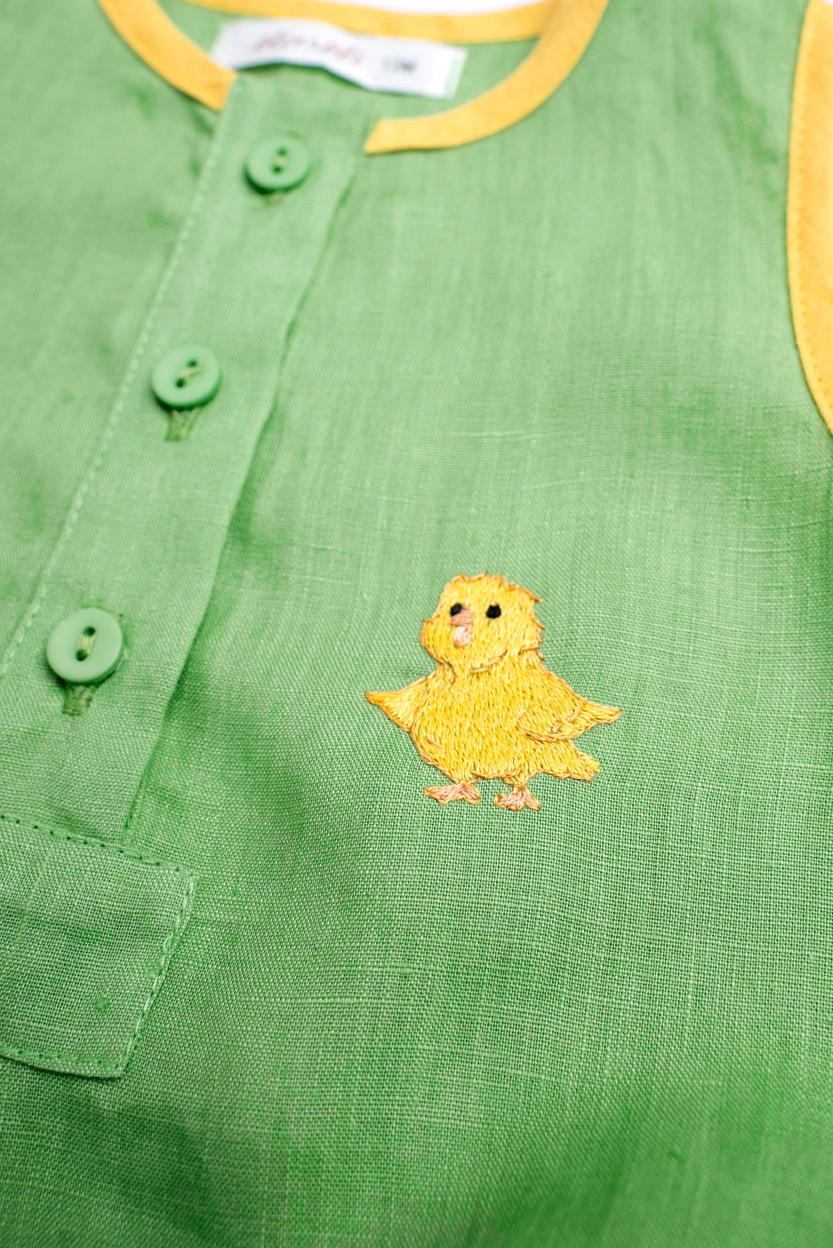 Detalhe do bordado à mão de canarinho em macaquinho bebê de linho verde e amarelo