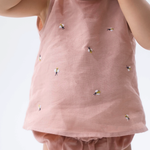 Detalhe da Regata Duda para bebê em 100% linho rosa antigo, com pequenas abelhas bordadas à mão e tapa-fralda.