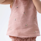 Detalhe da Regata Duda para bebê em 100% linho rosa antigo, com pequenas abelhas bordadas à mão e tapa-fralda.