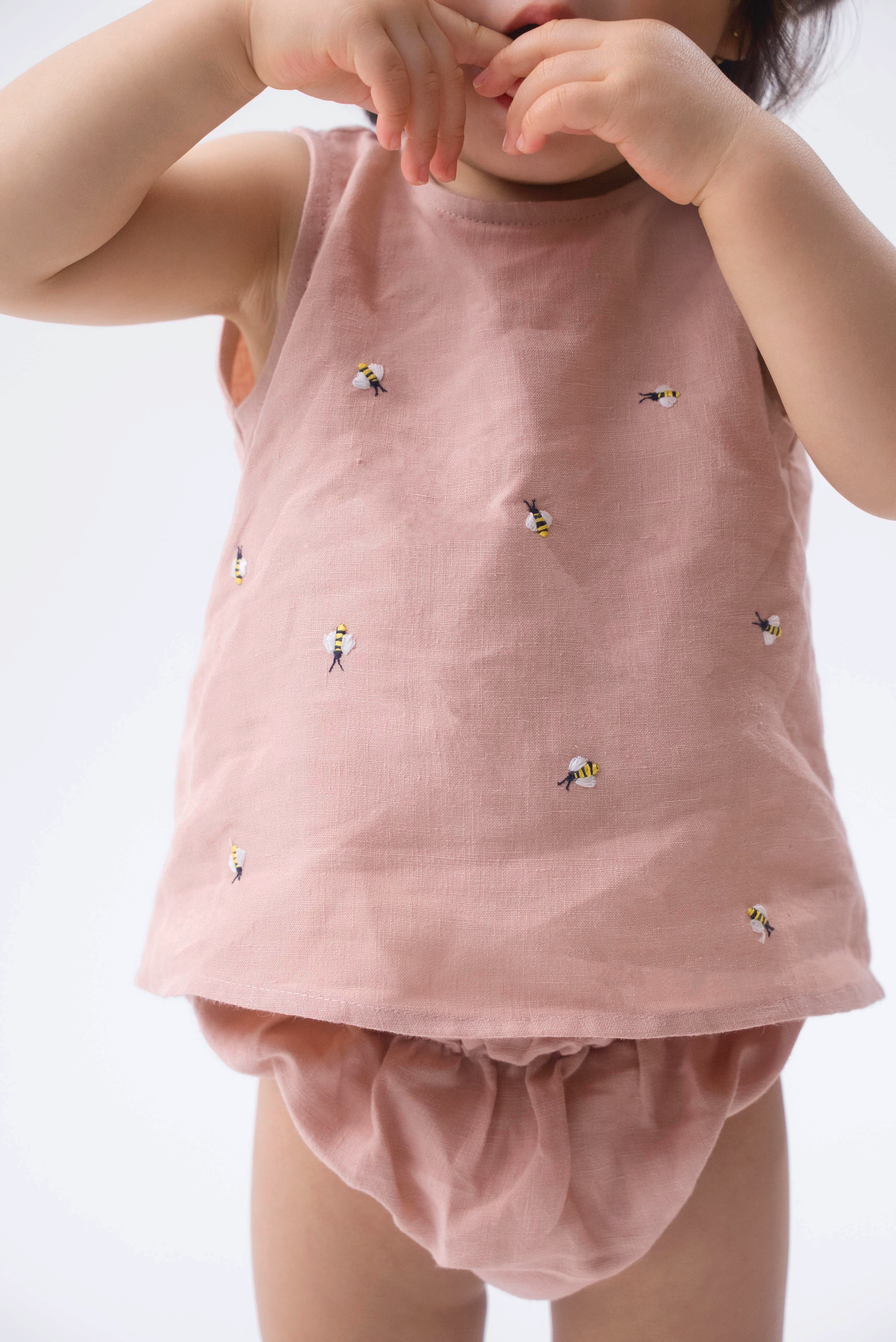 Detalhe da Regata Duda para bebê em 100% linho rosa antigo, com pequenas abelhas bordadas à mão e tapa-fralda.