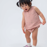 Bebê vestindo Regata Duda em linho rosa antigo bordada com abelhas e tapa-fralda no mesmo tecido.